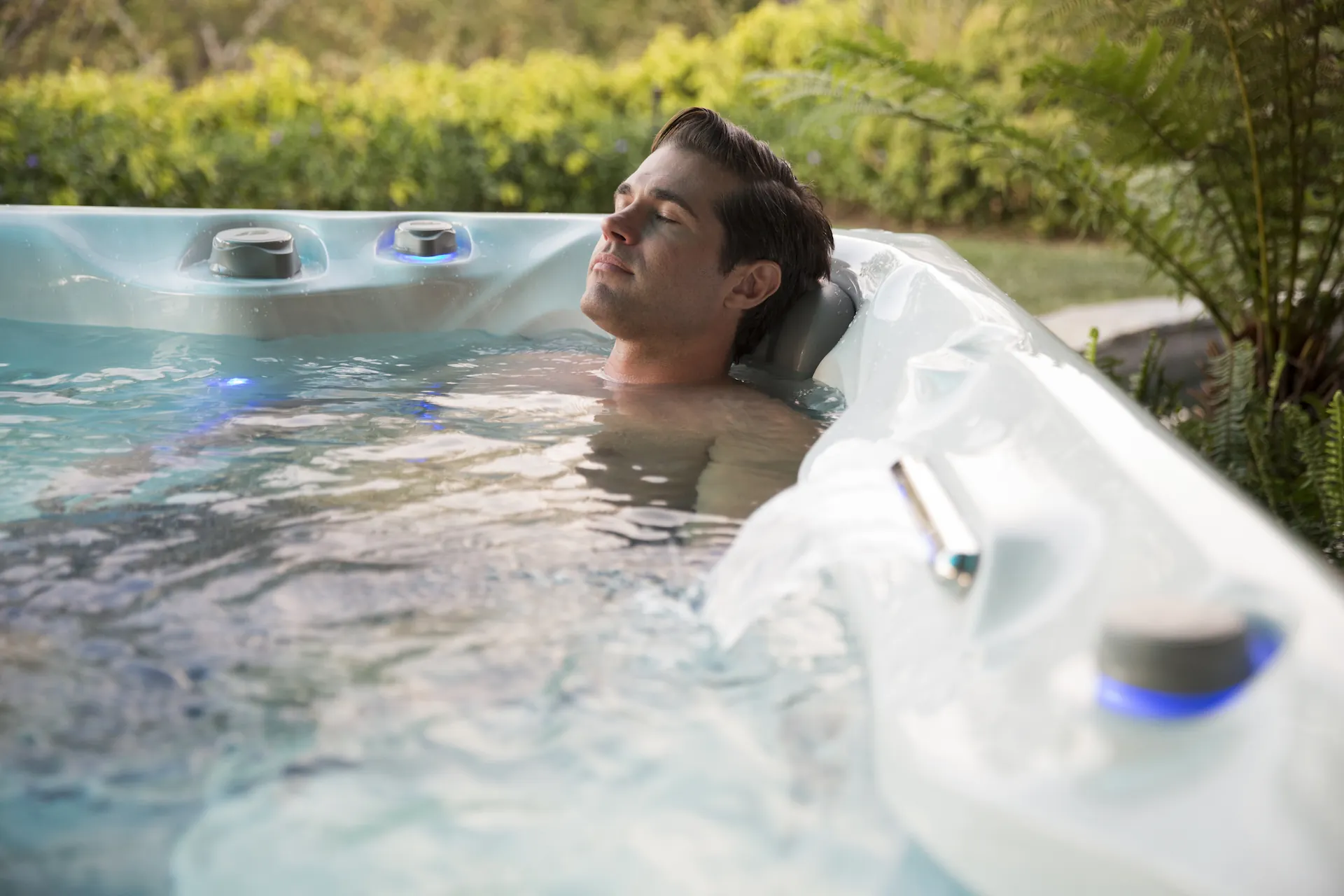 A bather sits in a corner seat of a hot tub outdoors in the daylight. Your previous experience in hot tubs helps answer the question "How often should I use a hot tub?"