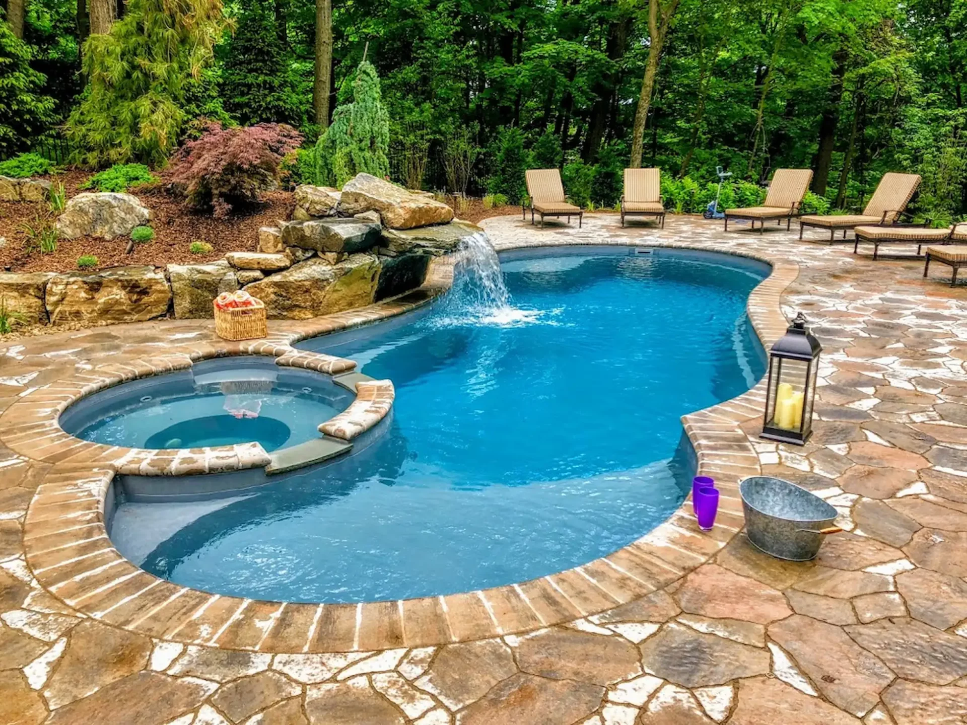 A curvy inground swimming pool with light blue liner sits in the Pennsylvania daylight. Shape and color are two of the design factors to consider when asking "Should I modernize my swimming pool with something trendy or classic?"