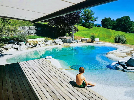 A child sitting next to a stunning backyard beach pool.