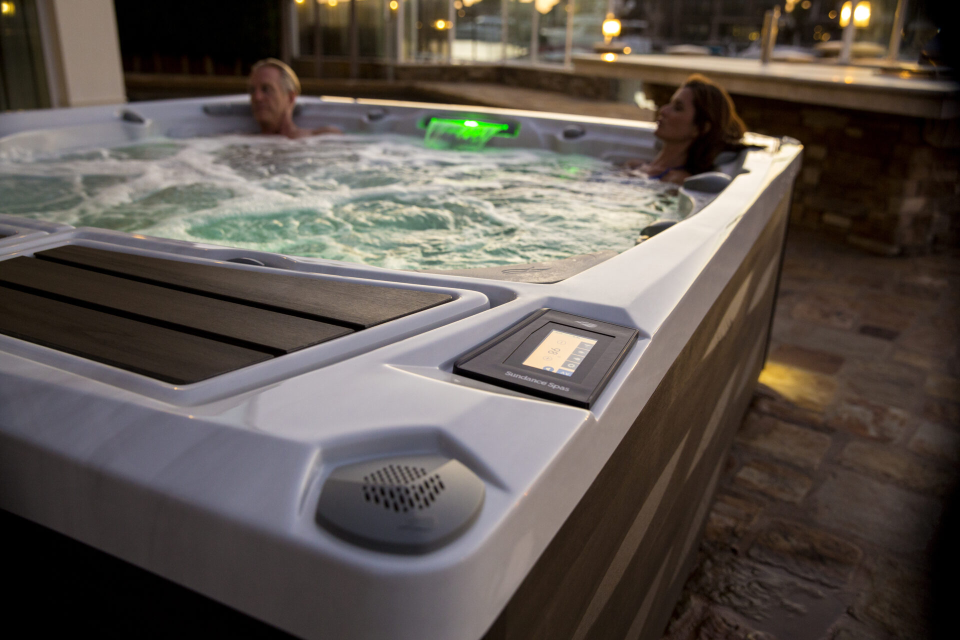 A couple sitting in a hot tub. You can see the control panel showing the hot tub temperature